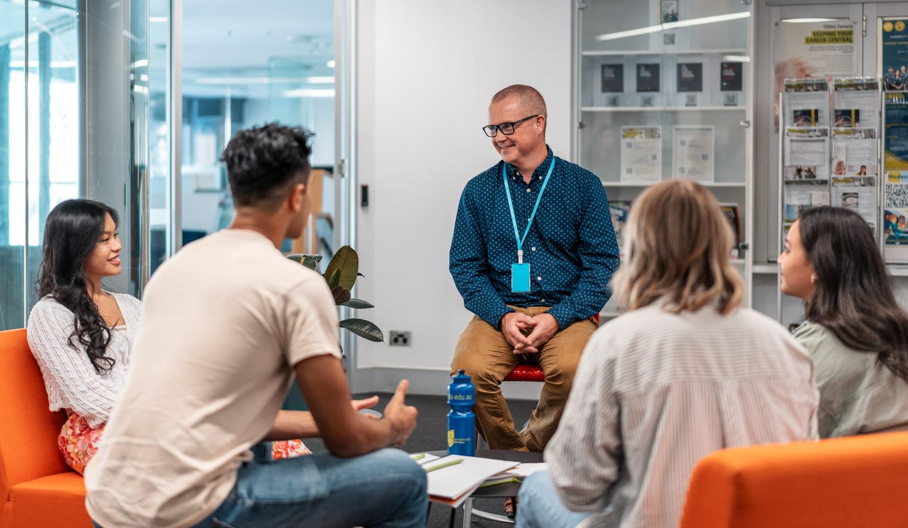 Students sitting in a library lounge space talking with an industry professional