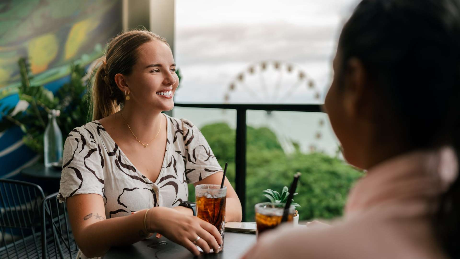 Student sitting at table with a drink looking to the side smiling