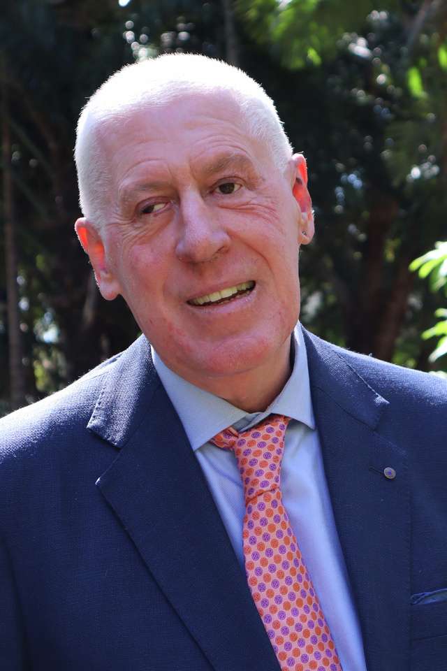 Chancellor, Graeme Innes standing on the Rockhampton campus smiling at the camera