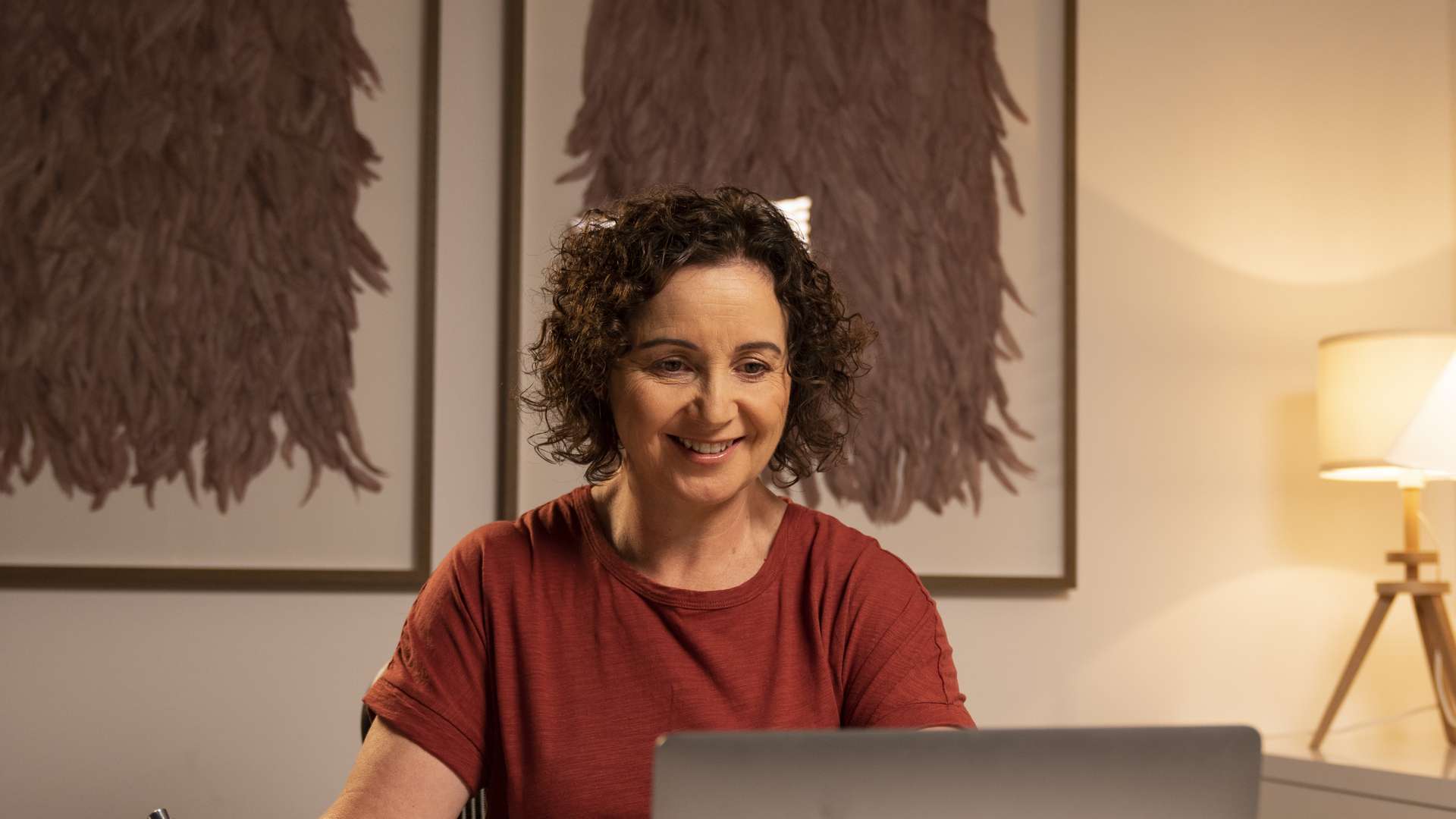 CQU student studying at home using her laptop computer with notepad next to her.