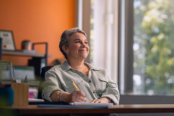 person sitting at a desk in an office with a pen in their handjpg