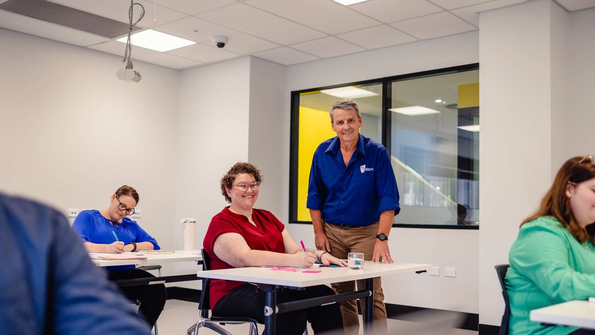 A CQU student is helped by a teaching staff member in a classroom.