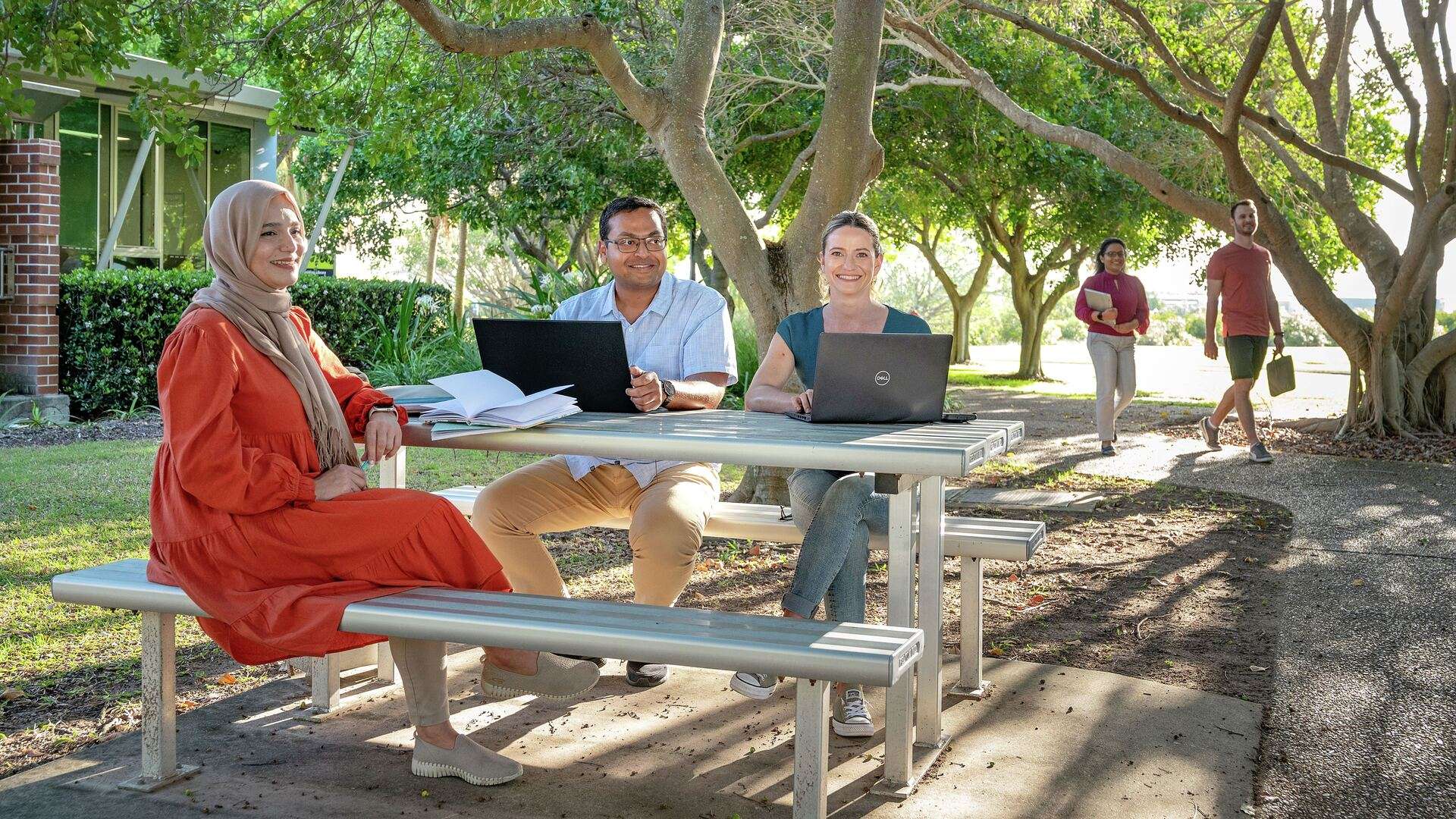 Students studying at a picnic table under the trees on Gladstone campus grounds