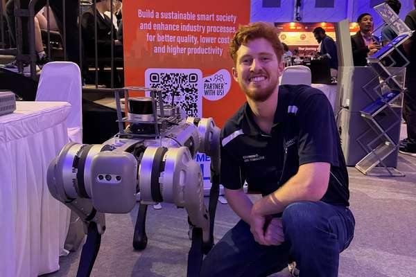 Logan Crosby crouching down next to a robot