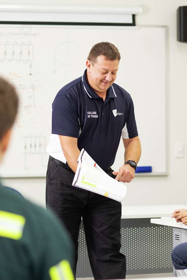 CQU TAFE teacher shows a student study materials in the classroom.