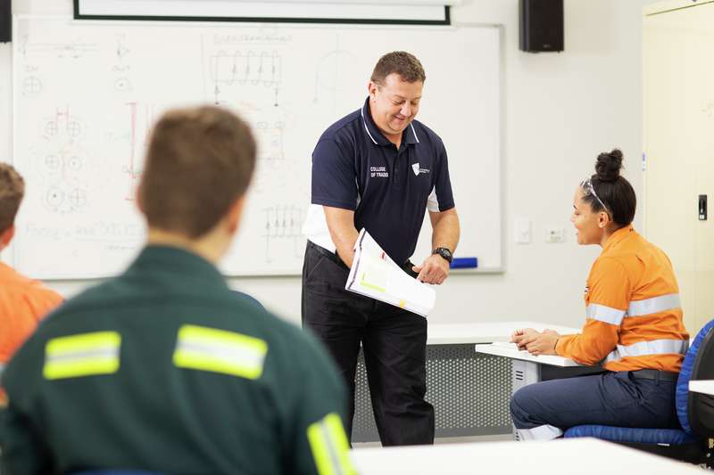 CQU TAFE teacher shows a student study materials in the classroom.