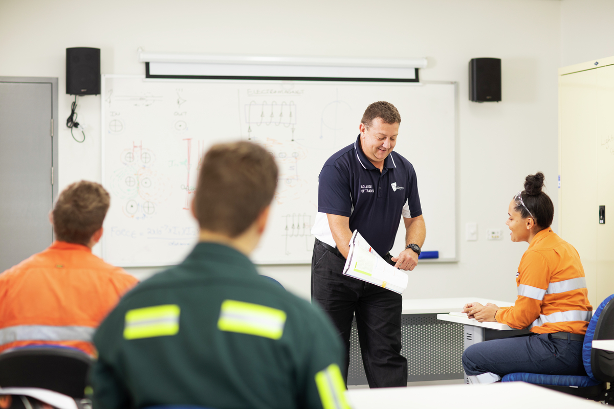 CQU TAFE teacher shows a student study materials in the classroom.