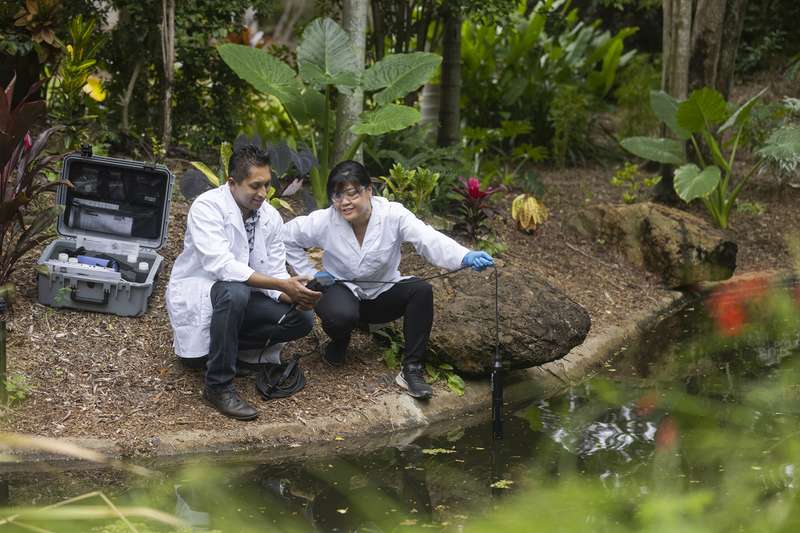 Two agriculture research students collecting data from a pond