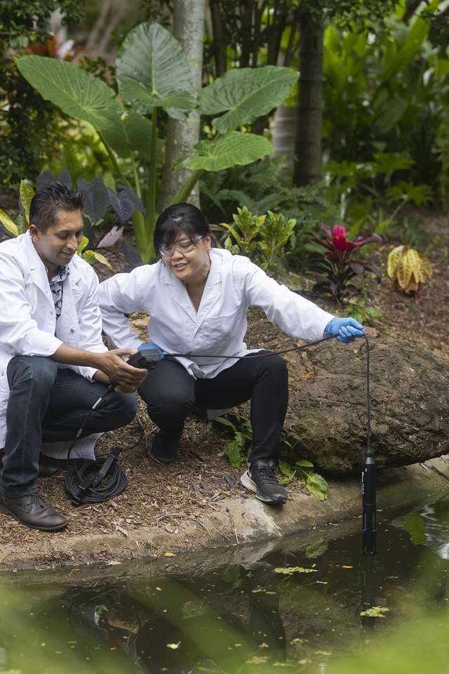 Two agriculture research students collecting data from a pond