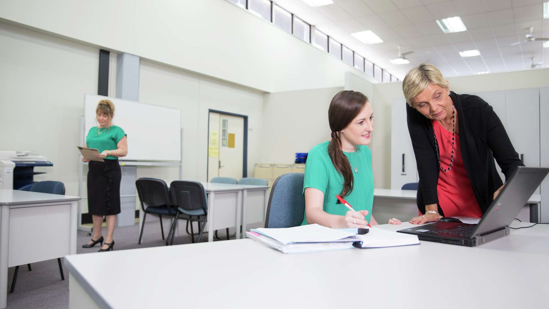 A student learning in a classroom from their tutor on their laptop