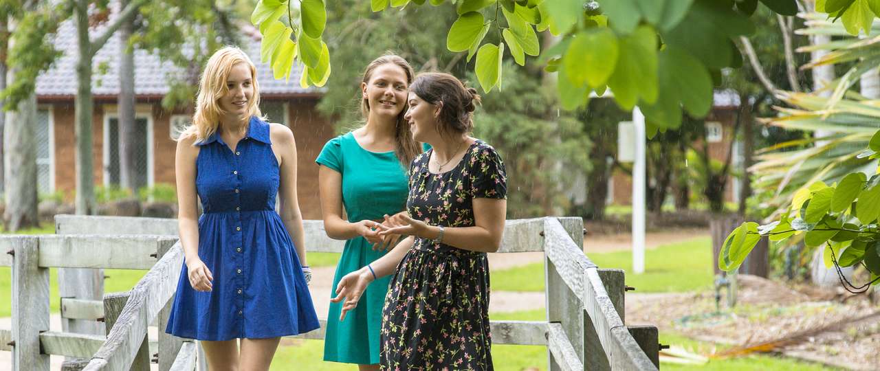 Three CQU students walking through the Rockhampton campus and smiling