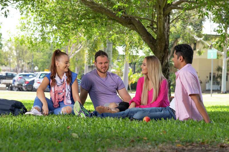 Rockhampton students sitting and chatting under the trees on campus grounds