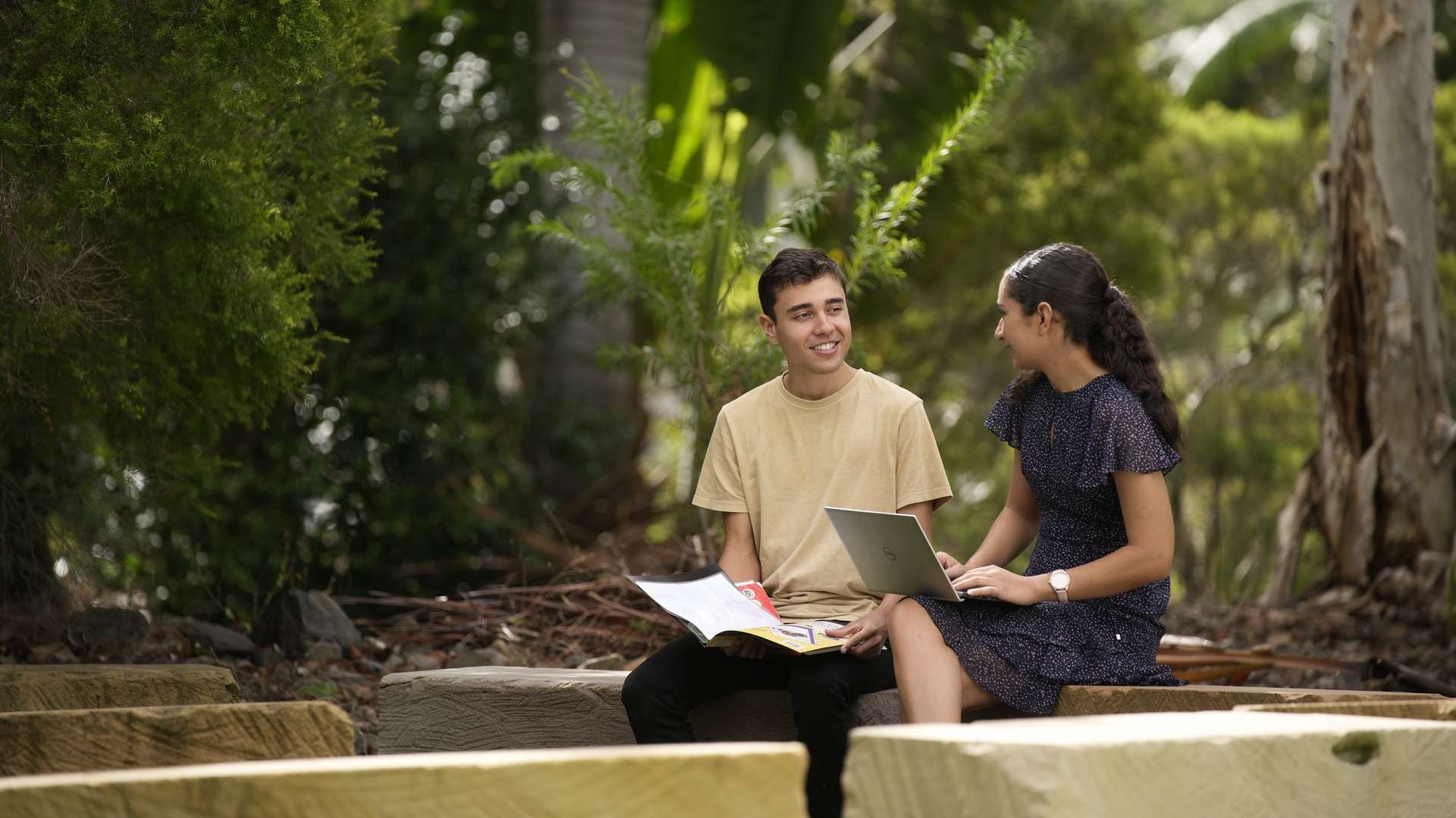Two students studying and talking amongst each other whilst sitting in a yarning circle.