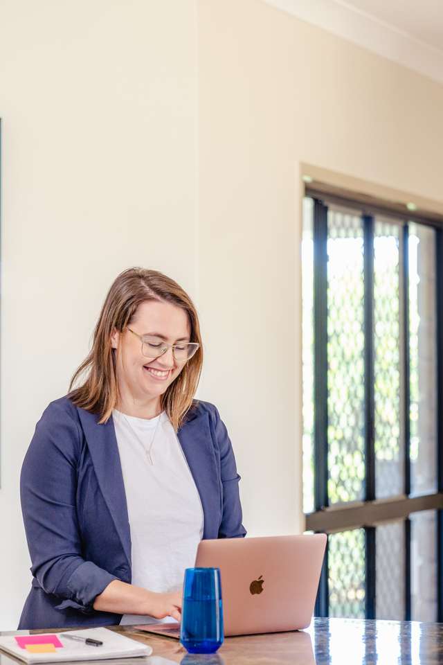 A mature age student typing on a laptop at a bench top at home